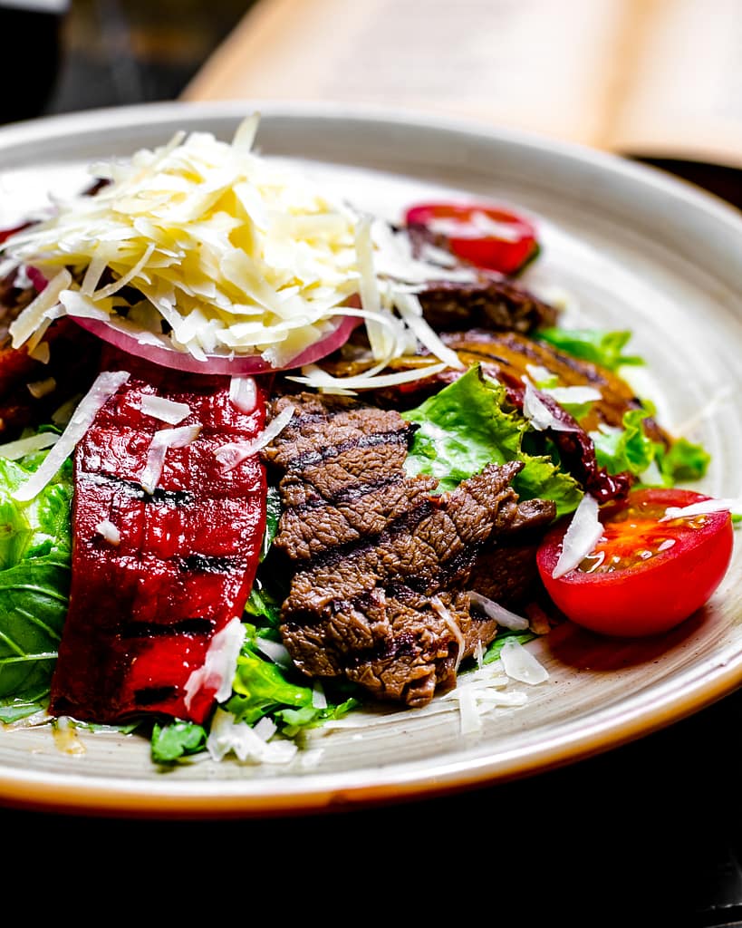 close front view grilled meat with vegetables and lettuce with grated cheese on a plate
